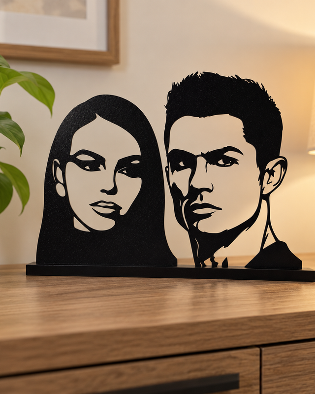 Portrait décoratif noir ajouré de deux personnes sur un socle rectangulaire.