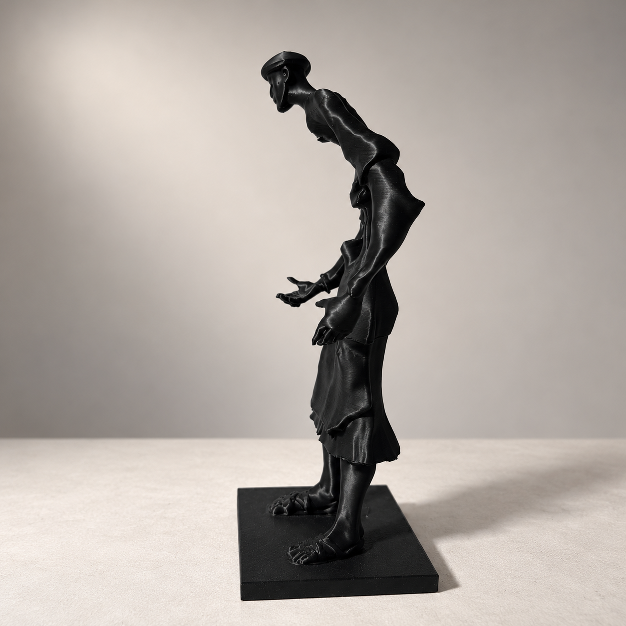 Statuette noire élancée du Guerrab de Meknès, vue de face sur socle rectangulaire.
