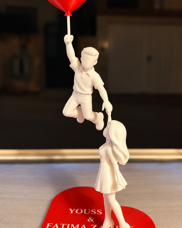 Couple blanc avec ballon cœur rouge sur une base cœur portant des noms et une date en exemple.