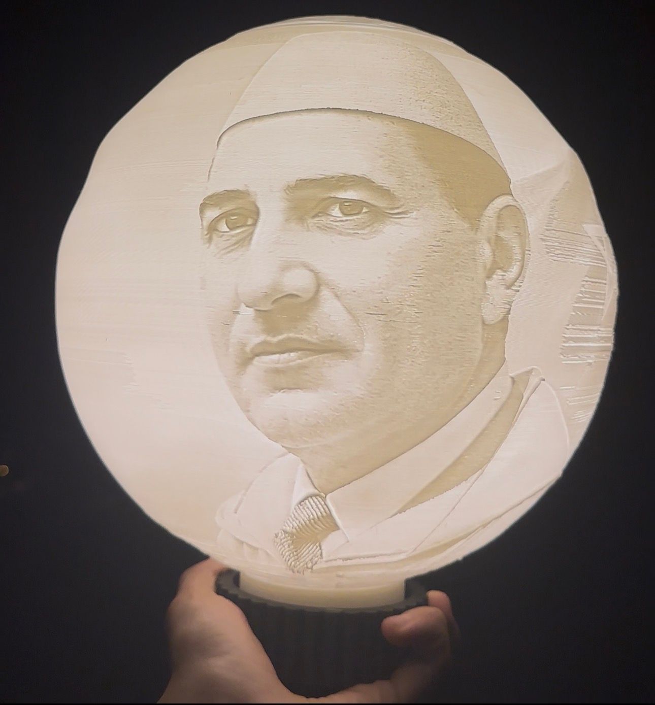 Lampe ronde lumineuse avec portrait en tons clairs et base sombre, tenue à la main ; exemple de photo personnalisée.