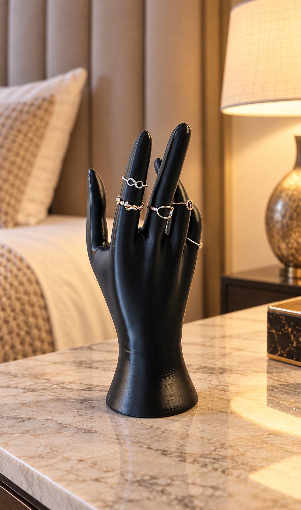 Main porte-bijoux noire dressée, présentant plusieurs bagues sur ses doigts.