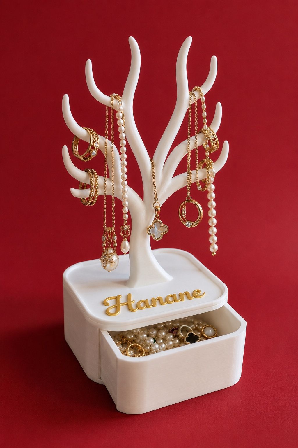 Arbre porte-bijoux blanc avec tiroir ouvert, bijoux exposés et prénom Hanane donné en exemple.