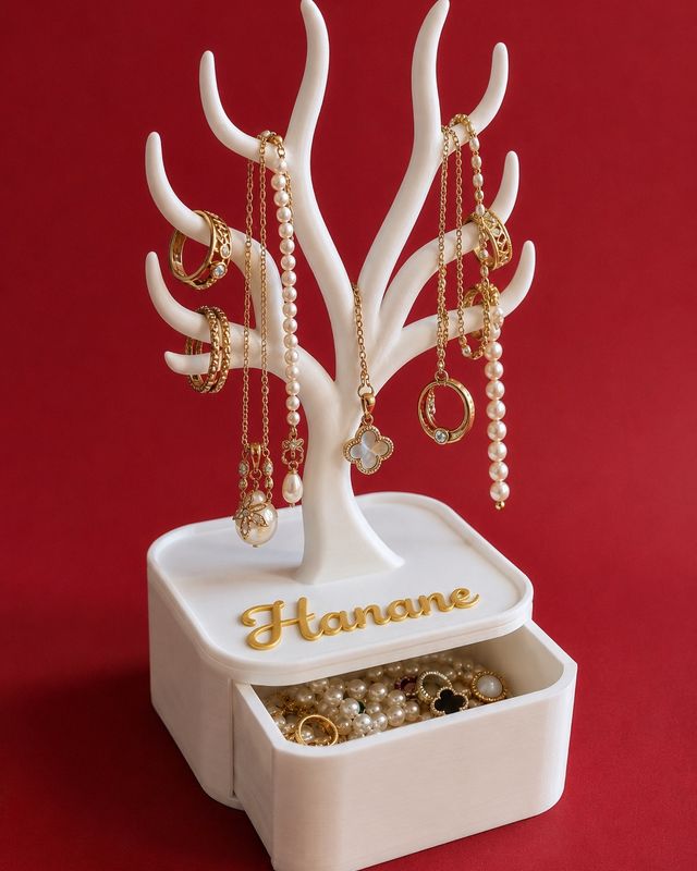 Arbre porte-bijoux blanc avec tiroir ouvert, bijoux exposés et prénom Hanane donné en exemple.