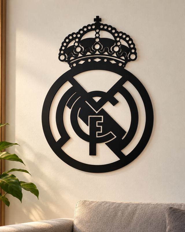 Écusson mural noir du Real Madrid, avec couronne et lettres entrelacées, sur un mur clair.